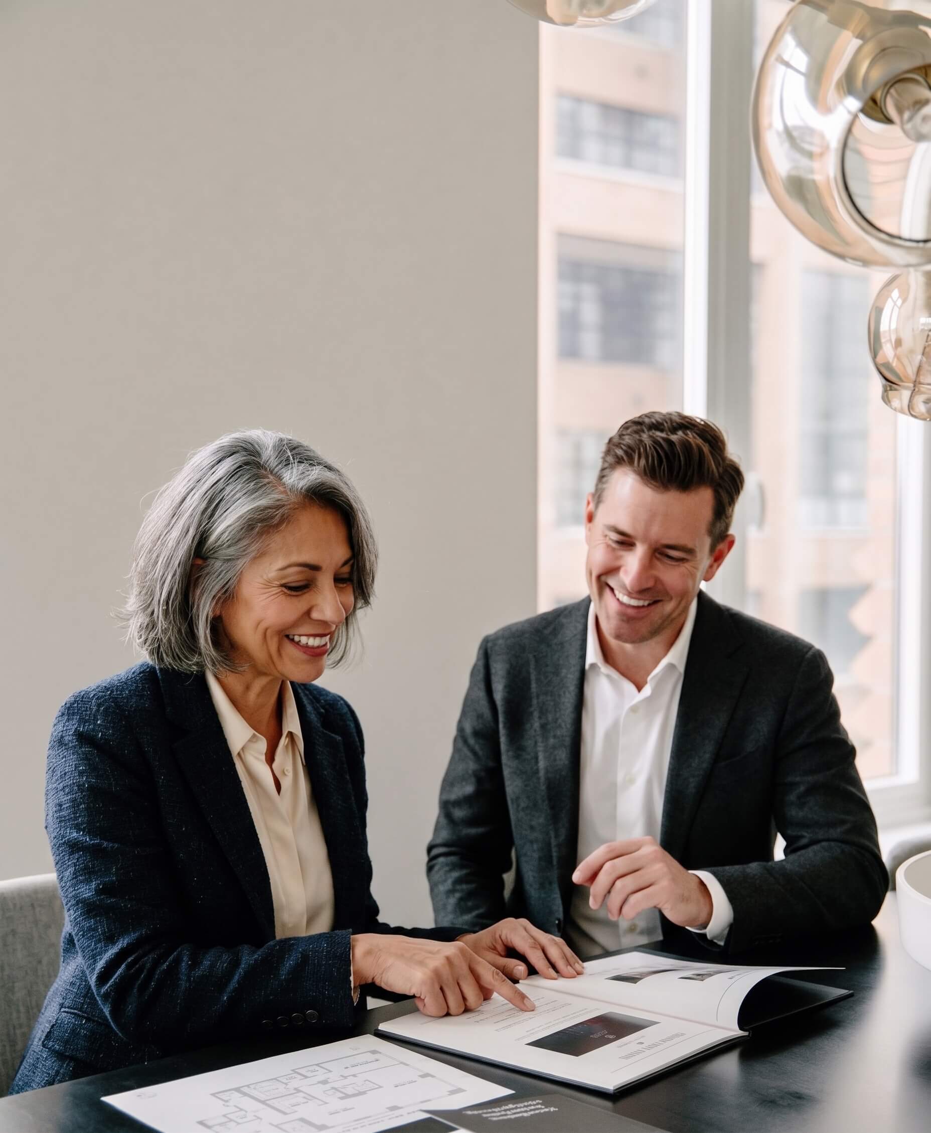 Two professionals collaborating at a desk, reviewing work together